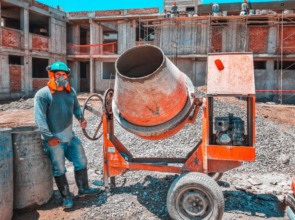 worker with gas mask operating concrete mixer