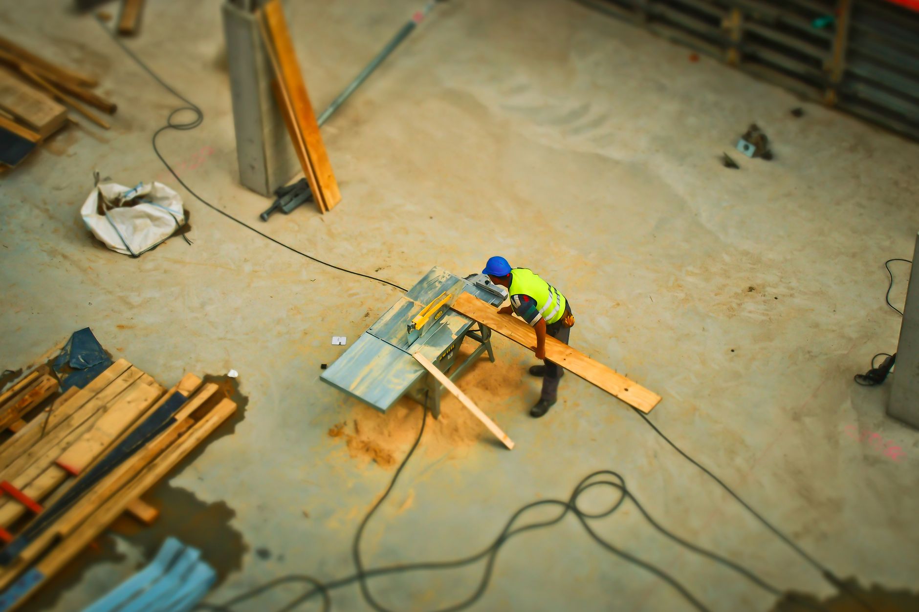person cutting wood on table saw during daytime