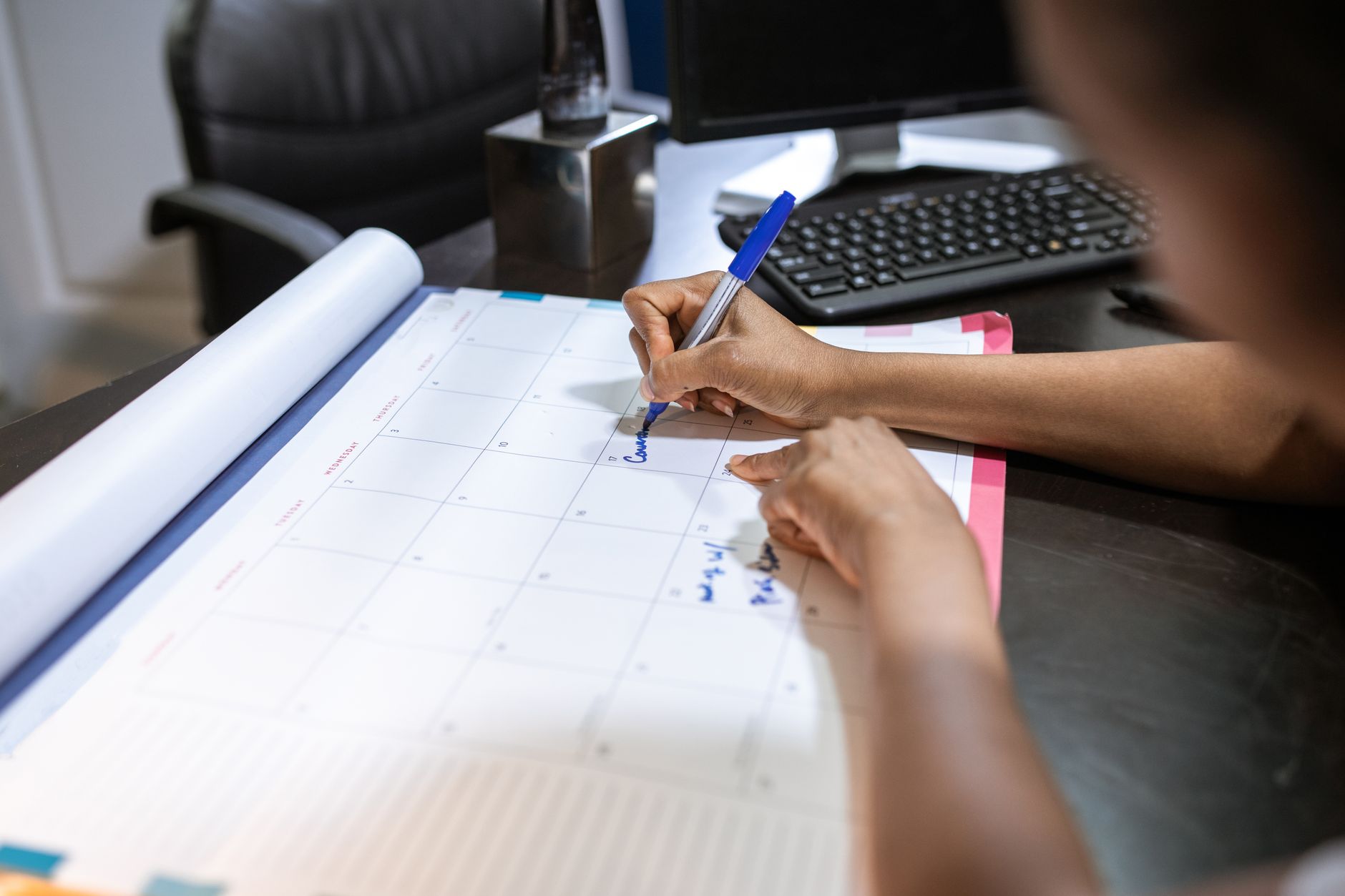 a person writing on a desk calendar
